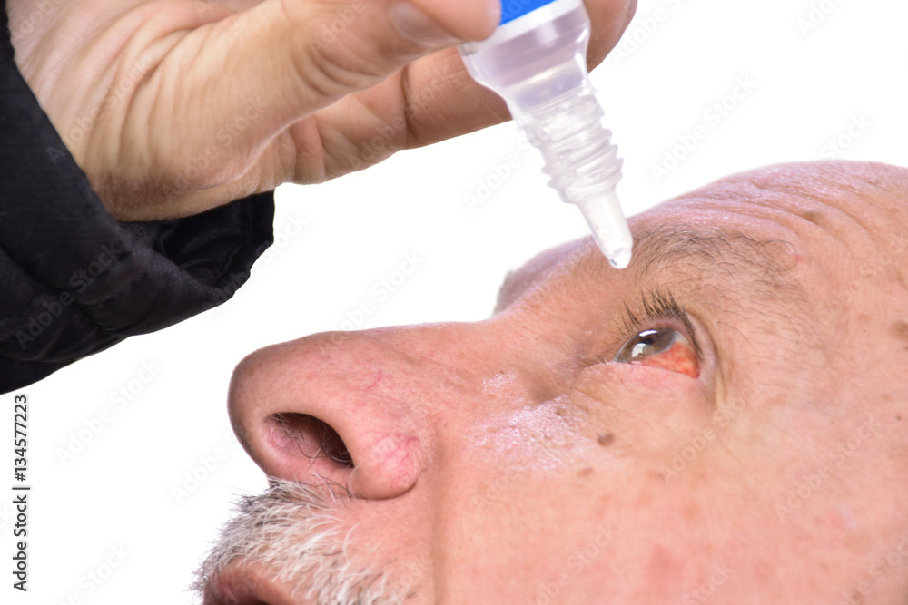 Senior man dripping a red eye with eye drops