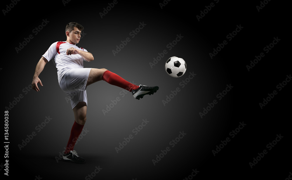 Football player is kicking a ball on the black background. Football player is kicking a ball on the black background.