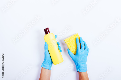 Female hands in blue rubber gloves holding a yellow bottle of de