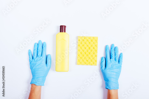 Female hands in blue rubber gloves, the yellow bottle of deterge photo