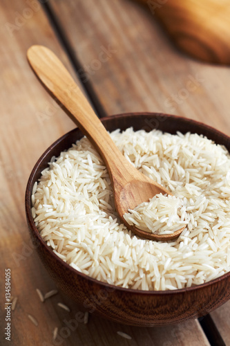 Raw uncooked basmati rice in wooden bowl on table photo