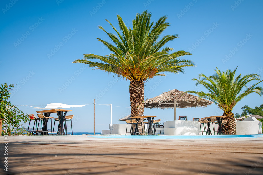 Fototapeta premium Beach with wooden umbrellas and sunbeds