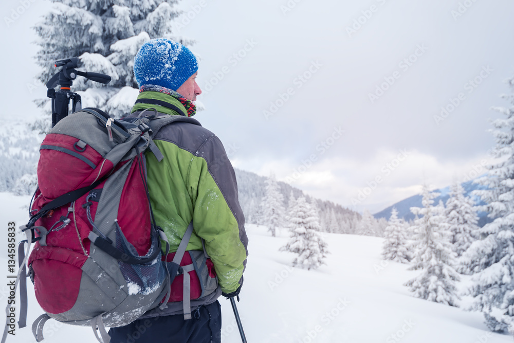 Man with backpack in snow covered forest