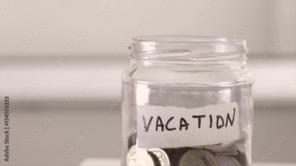 Inserting coins into vacation saving jar Inserting coins into vacation saving jar