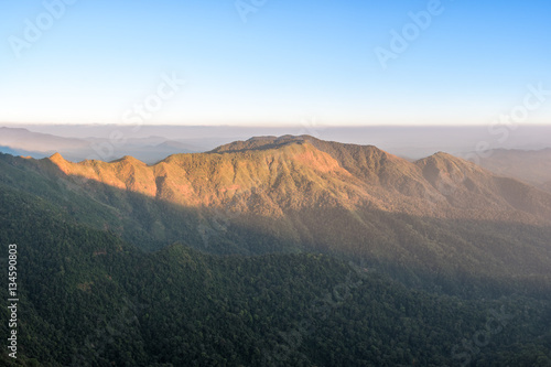 Mountain valley and forest during sunrise in haze day.