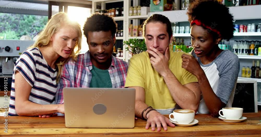Group of friends using laptop while having cup of coffee in café 4k Group of friends using laptop while having cup of coffee in café 4k