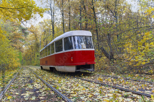 Red tram rides in autumn park. Kiev, Ukraine