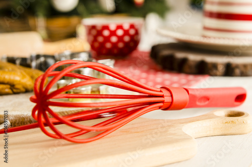 Red colorful whisk for whipping on the table and hommade daught in kitchen. Beautiful kitchen with tools for cooking photo