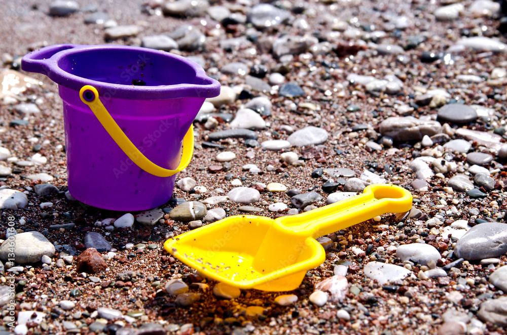Small baby toy bucket and yellow shovel lying on the beach. Small baby toy bucket and yellow shovel lying on the beach.