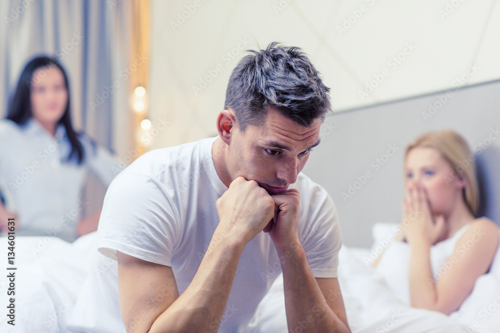 man sitting on the bed with two women on the back man sitting on the bed with two women on the back