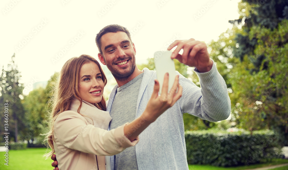 Fototapeta premium happy couple with smartphone taking selfie in park