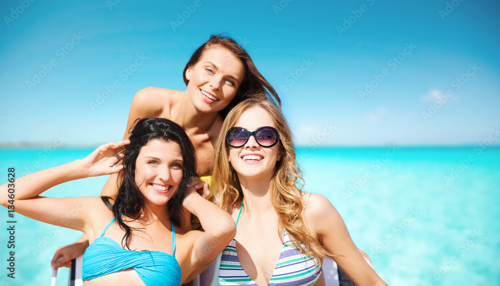 happy young women in bikinis on summer beach