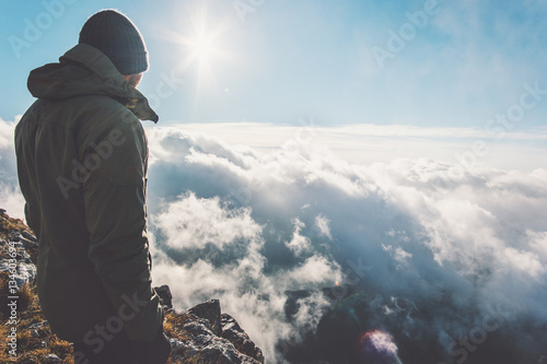 Man on mountain summit with sun over clouds Travel hiking Lifestyle success concept adventure active vacations outdoor