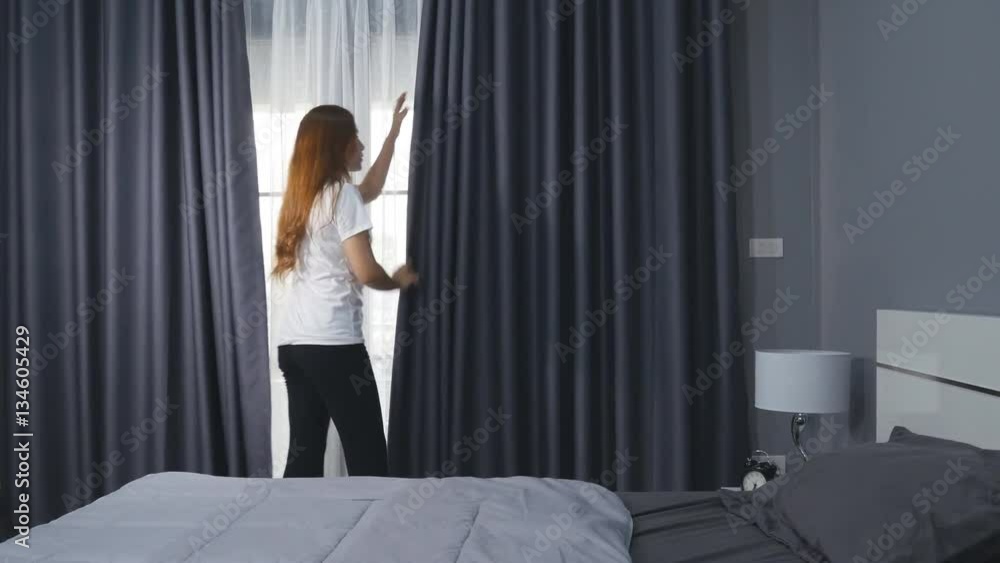 Woman coming to the window in the morning, opening curtains and let the light in the room Woman coming to the window in the morning, opening curtains and let the light in the room