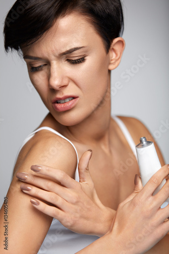 Injury Treatment. Beautiful Woman With Arm Pain  Applying Cream