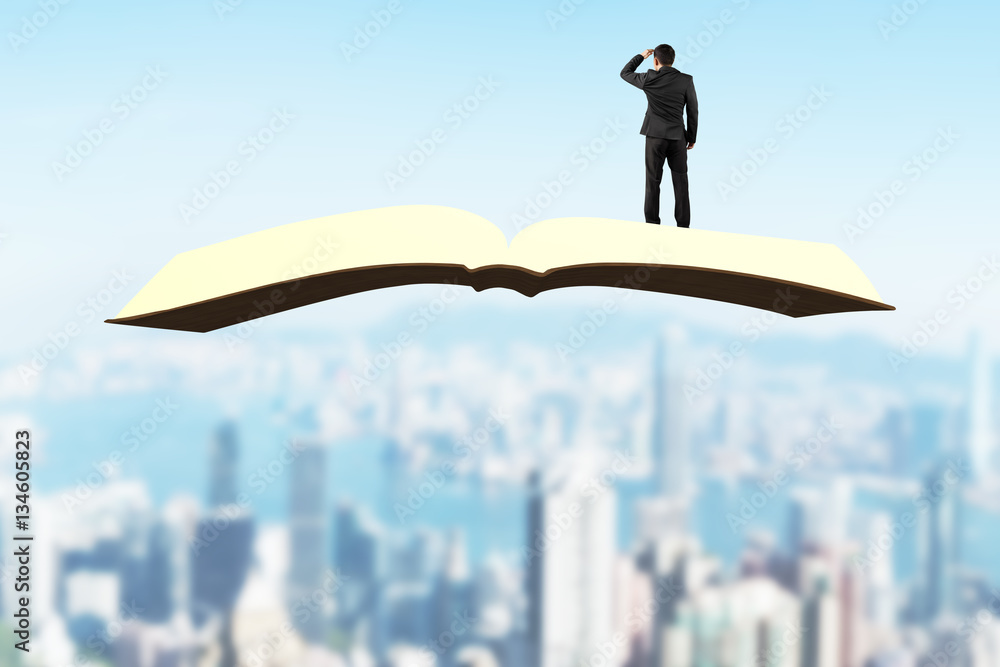 Man standing and gazing on book flying over city Man standing and gazing on book flying over city