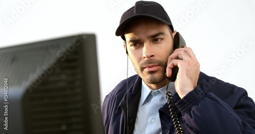 Security guard receiving call while working on computer at counter 4k
