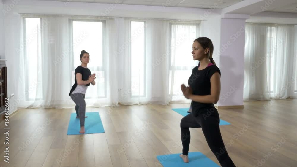 Three women doing warrior pose yoga class Three women doing warrior pose yoga class