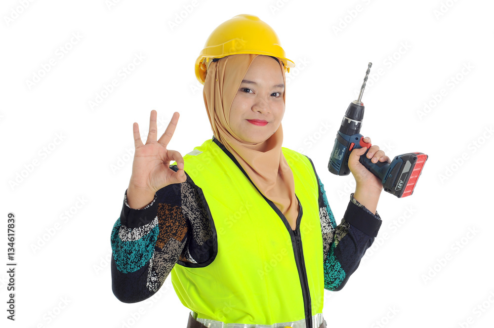 Construction worker wear yellow safety helmet shows okay sign while hold cordless drill Construction worker wear yellow safety helmet shows okay sign while hold cordless drill
