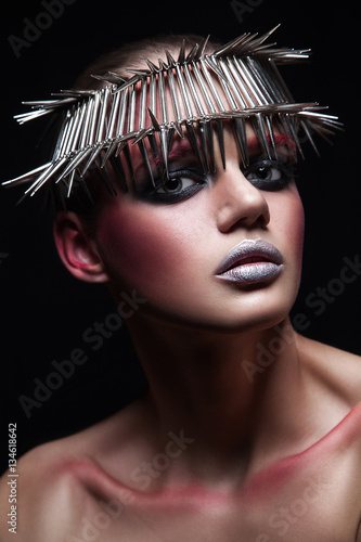 fashion beauty model with metallic headwear and shiny silver red makeup and blue eyes and red eyebrows on black background