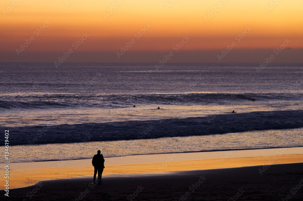 Couple at beach by dusk watching surfers