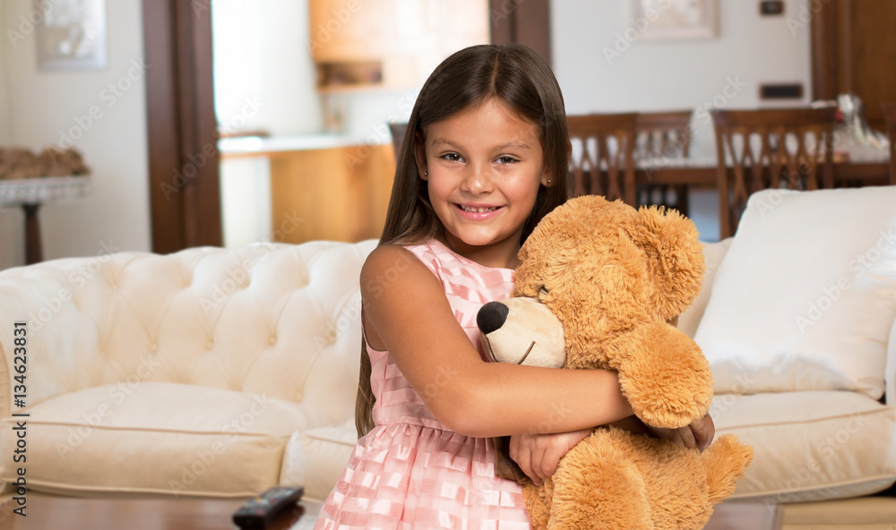 Smiling little girl holding a teddy bear - obrazy, fototapety, plakaty 