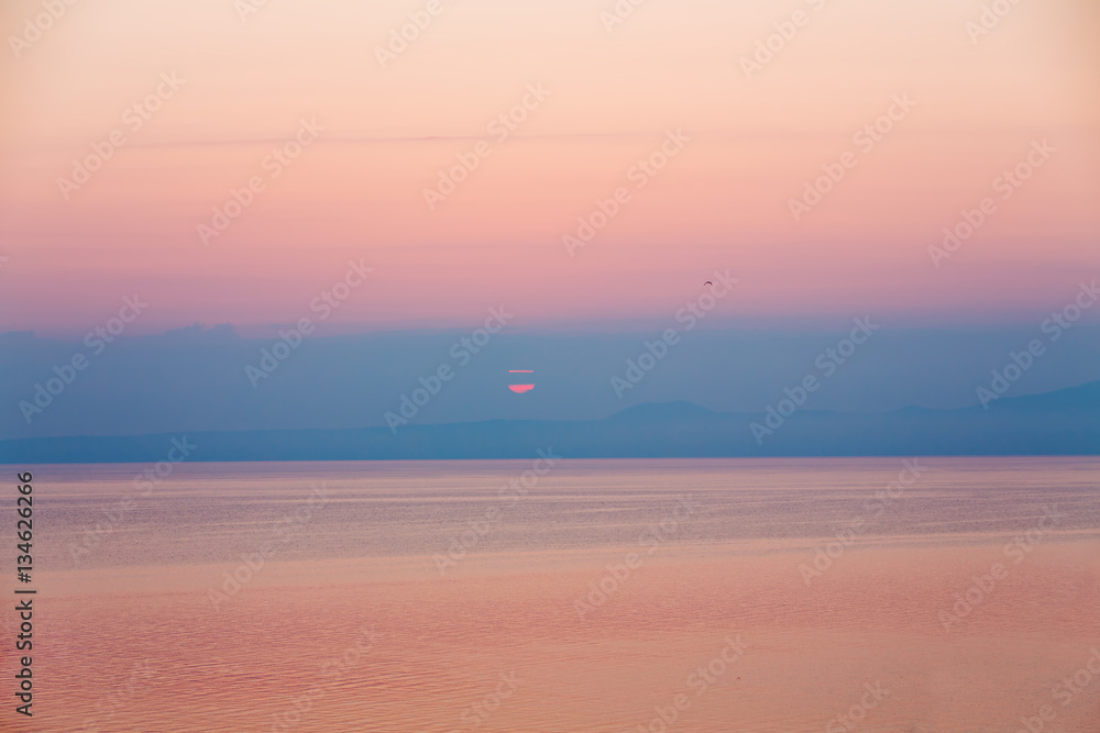 Obraz premium sunrise falling behind mountains on greek island