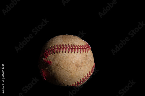 A used baseball on a black background