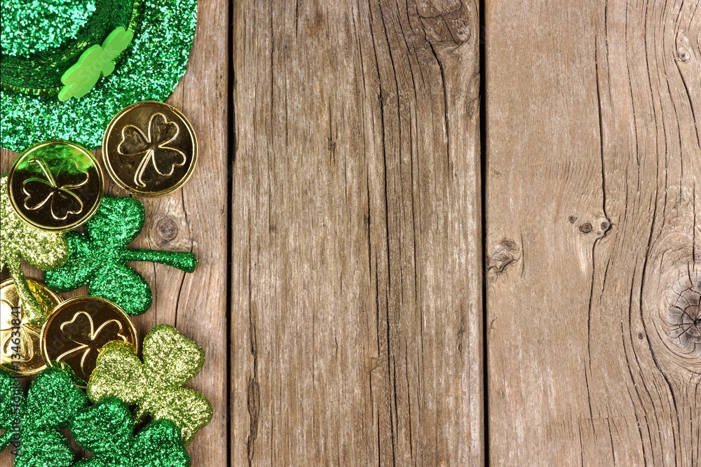 St Patricks Day side border of shamrocks, gold coins and leprechaun hat over rustic wood St Patricks Day side border of shamrocks, gold coins and leprechaun hat over rustic wood