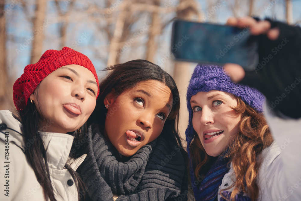 Group of girl friends enjoying taking selfies in the snow in winter