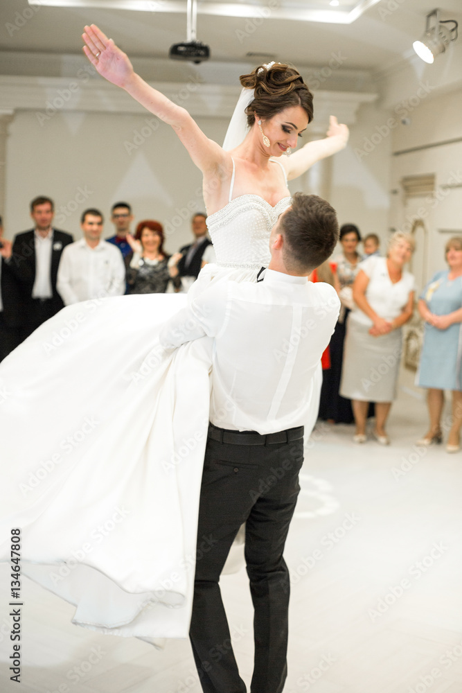 Bride spreads her hands while groom whirls her in a dance
