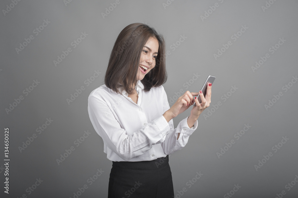 Beautiful business Woman using smartphone on grey background Beautiful business Woman using smartphone on grey background