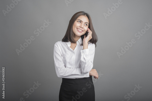 Beautiful business Woman using smartphone on grey background © tonefotografia