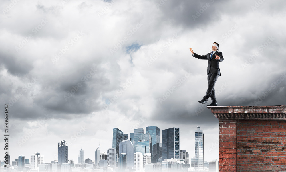 Danger and risk concept with businessman making step from edge Danger and risk concept with businessman making step from edge