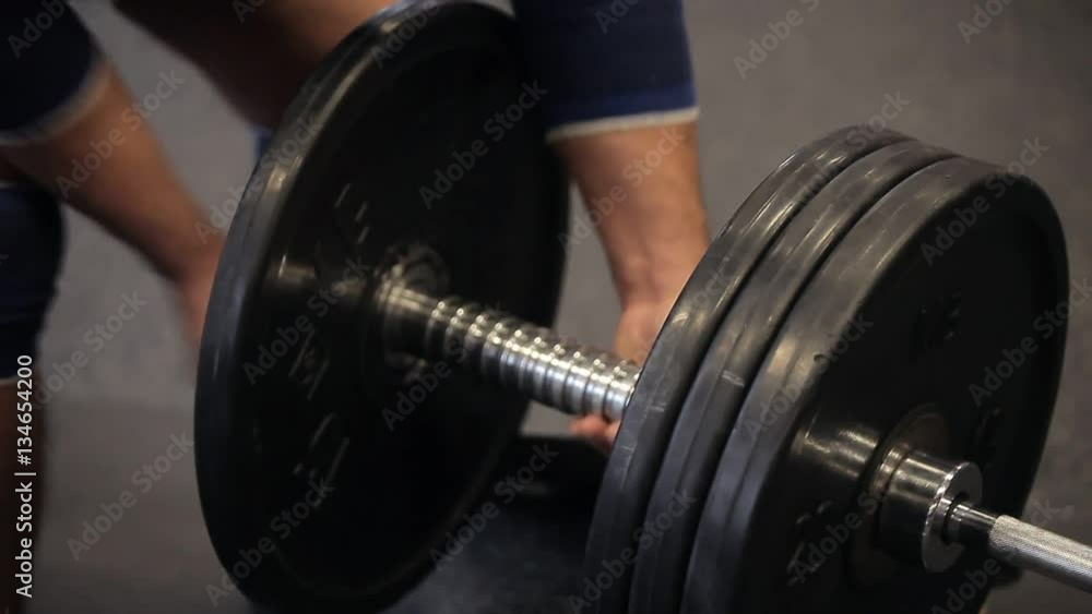 Transition shot of determined muscular man putting heavy plates on barbell and lifting in gym.Young sporty man preparing for weight lifting in a crossfit gym. Preparing Transition shot of determined muscular man putting heavy plates on barbell and lifting in gym.Young sporty man preparing for weight lifting in a crossfit gym. Preparing