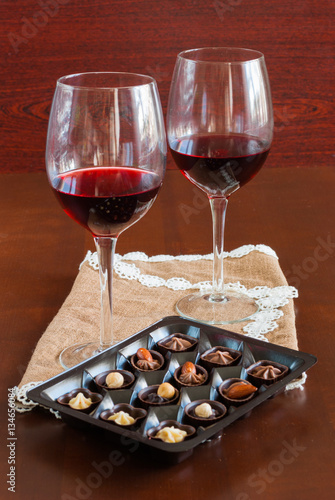 Two glasses of wine on a wooden table.  Candies.