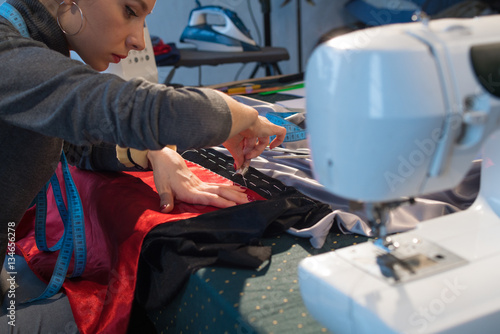 The dressmaker sews a jacket made of satin