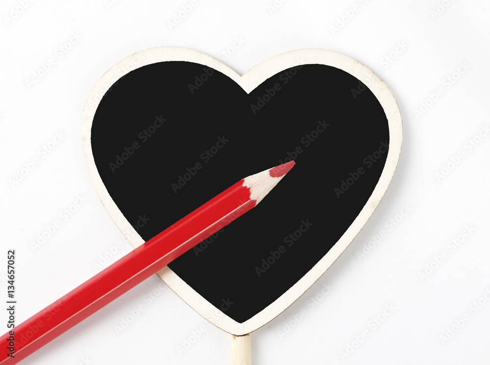Red wooden pencil on a blackboard with heart shape on white background Red wooden pencil on a blackboard with heart shape on white background