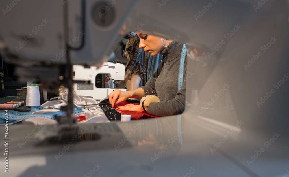 View through a sewing machine. She sews.