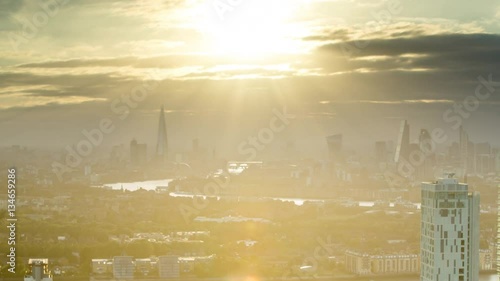 a sunset timelapse of the city of london skyscapers, zoomed in from a high vantage point far away. amazing sunrays are captured during this scene photo