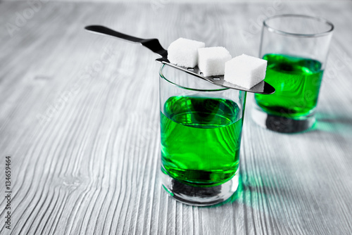 absinthe with sugar cubes and spoon on wooden background
