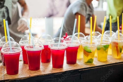 Various soft drinks in plastic cups with a straws on display at a street market. Selective focus