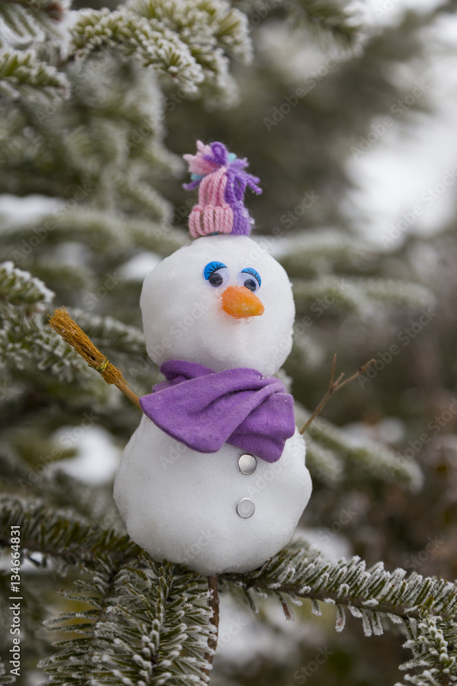 Little snowman standing on christmas tree.
