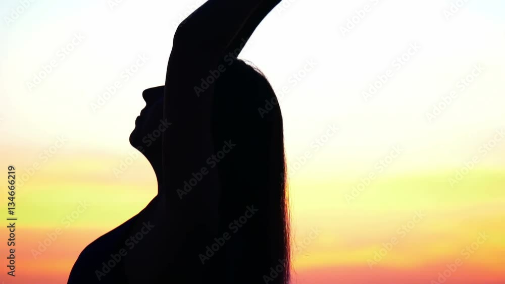 Woman performing yoga on the beach at dusk Woman performing yoga on the beach at dusk
