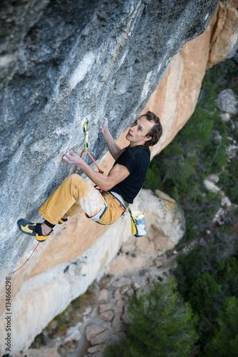 Outdoor sport. Rock climber ascending a challenging cliff. Extreme sport climbing.