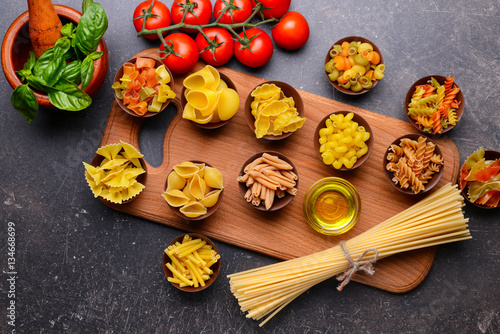 Different kinds of pasta in bowls on color background