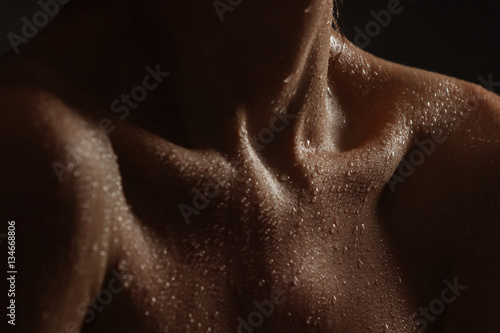 Sexy female body with drops of water on dark background. Low key. Sexy naked breasts. Nude.