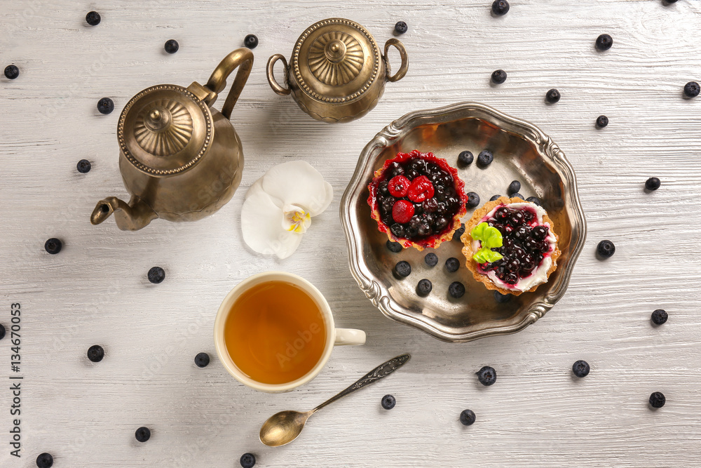 Tray with delicious cakes and cup of tea on white table - obrazy, fototapety, plakaty 