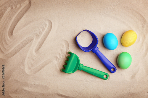 Easter eggs with rake on sand