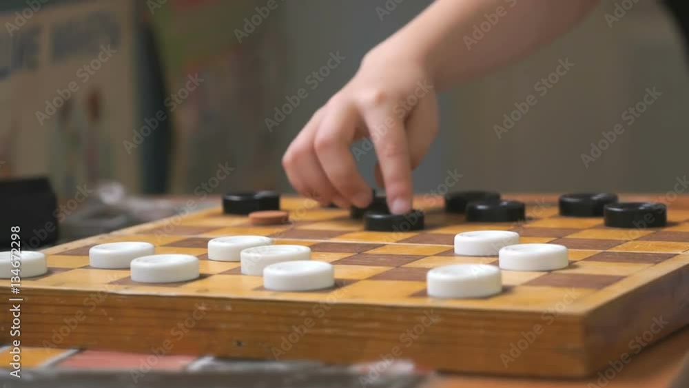 Kids sit at the table and play checkers at the garden. Close-up Kids sit at the table and play checkers at the garden. Close-up